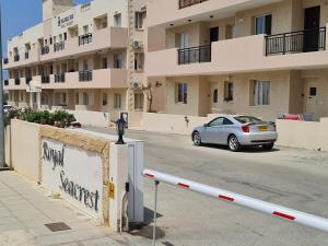 帕福斯Front pool garden apartment的停在建筑物前停车场的汽车