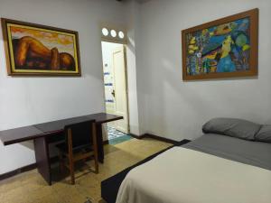 a bedroom with a bed and a desk and a painting at Casa Prado Centro in Medellín