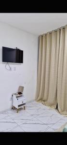 Zimmer mit einem TV, einem Tisch und Vorhängen in der Unterkunft Casa aconchegante e bem localizada - São Brás in Belém