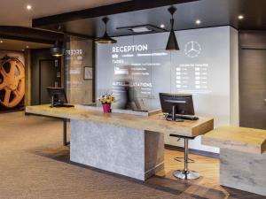 a reception counter with two computers on a wall at ibis Saint Dizier in Saint-Dizier