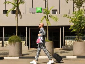 a man walking down a street with a suitcase at Ibis Styles Abidjan Plateau in Abidjan