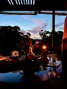 une table avec un vase dessus, offrant une vue sur le coucher du soleil dans l'établissement Mulberry Grove Retreat, à Tryphena