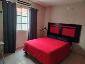 a red bed in a room with a window at Bonaterra in El Jobo