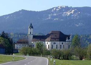 a large white building with a clock tower next to a road at Abendsonne in Lechbruck