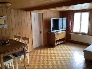 Una sala de estar con televisión y una mesa de comedor. en Mannried 2 1 2 Zimmerwohnung Rustikal, en Zweisimmen