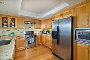 a kitchen with wooden cabinets and a stainless steel refrigerator at 152-4 Coastal Luxury with Panoramic Ocean View in Oceanside