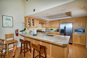 a kitchen with wooden cabinets and a stainless steel refrigerator at 152-4 Coastal Luxury with Panoramic Ocean View in Oceanside