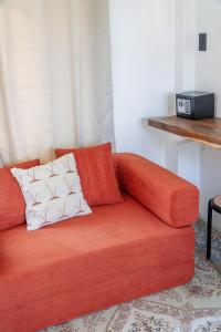 ein orangefarbenes Sofa mit zwei Kissen darauf in einem Zimmer in der Unterkunft CIELO Siargao in General Luna