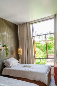 ein Schlafzimmer mit zwei Betten und einem großen Fenster in der Unterkunft CIELO Siargao in General Luna