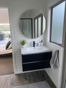 a bathroom with a sink and a mirror at Stylish Lake Ōkāreka Retreat Views, Spa in Rotorua in Rotorua