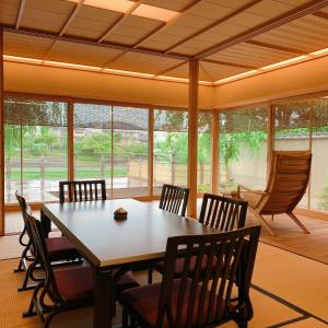 ein Esszimmer mit Tisch und Stühlen und Fenstern in der Unterkunft Maru Izumiyacho in Kyoto