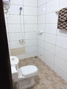 a white bathroom with a toilet and a sink at Paradis Douillet in Cotonou