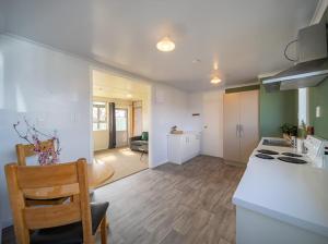 eine Küche und ein Wohnzimmer mit einer Theke und einem Tisch in der Unterkunft Te Anau Holiday House in Te Anau