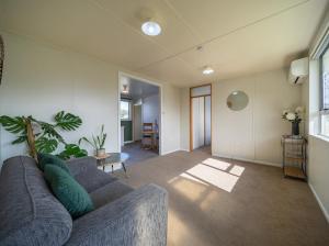 ein Wohnzimmer mit Sofa und Tisch in der Unterkunft Te Anau Holiday House in Te Anau