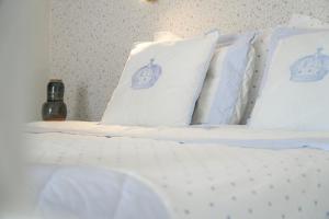 ein Bett mit weißen Kissen mit einer Krone darauf in der Unterkunft Casa da Imperatriz in Ilhabela