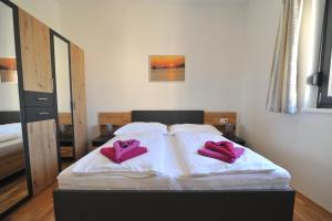 a bed with two pink pillows on top of it at Apartments with parking space Seline, Paklenica - 22077 in Starigrad-Paklenica