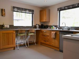 a kitchen with wooden cabinets and two stools at Glan-Y-Gors in Beddgelert +11 photos