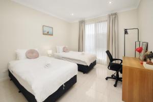 a hotel room with two beds and a desk at The Grand Six at Rochedale in Rochedale