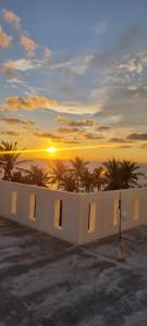 una puesta de sol sobre el océano con palmeras y un edificio en Secret Mirage, en Mirissa