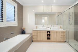 a bathroom with a tub and a sink and a mirror at The Grand Six at Rochedale in Rochedale +51 photos