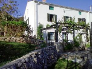 a white house with a stone wall in front of it at Gemütliches Ferienhaus Viskic in Supetarska Draga