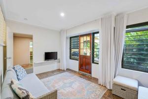 a living room with a couch and a tv at Edge Hill Apartment under Queenslander w Pool in Edge Hill
