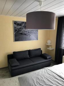 a living room with a black couch and a chandelier at Ferienhaus Am Weiher in Waltershausen