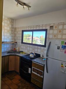une cuisine avec un réfrigérateur blanc et une fenêtre dans l'établissement Departamento amoblado Villa Gesell 3 cuadras de la playa, à Villa Gesell