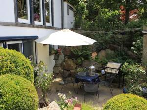 una mesa y sillas con una sombrilla en el jardín en Ferienwohnung Black For(r)rest Gumpp en Adelhausen