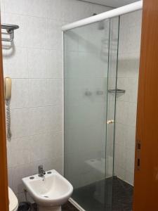 Un baño con lavabo y ducha de cristal. en Flat no Hotel Sol Alphaville, en Barueri