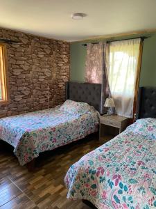 a bedroom with two beds and a stone wall at Las palmeras de Colbún in Colbún