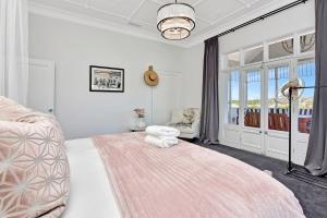 ein Schlafzimmer mit einem großen Bett mit einem rosa Teppich in der Unterkunft Merewether House 1910 - Iconic and Luxury Home in Merewether + 45 Fotos