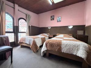 two beds in a bedroom with pink walls and windows at Hostal Tambo de Oro in La Paz