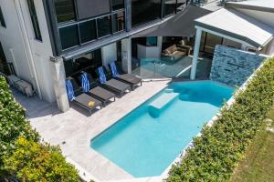 - une vue sur une piscine avec des chaises et un bâtiment dans l'établissement Beachfront with pool ocean views and pet friendly, à Buddina