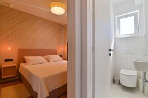 ein Schlafzimmer mit einem Bett und ein Badezimmer mit einem Waschbecken in der Unterkunft Ferienwohnung für 4 Personen ca 64 m in Trogir, Dalmatien Kaštela und Umgebung in Trogir