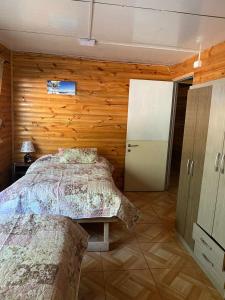 a bedroom with a bed and a wooden wall at Las palmeras de Colbún in Colbún +11 photos