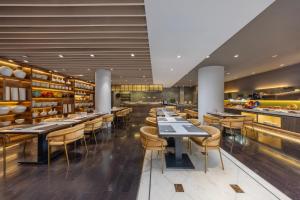 un restaurante con mesas y sillas y un bar en Metropolo Dahua Hotel Shanghai, en Shanghái