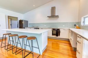 a kitchen with a white counter top and stools at 523 by the Sea in Broadwater +32 photos
