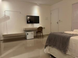 a bedroom with a bed and a desk with a tv on the wall at Pousada Paraíso Maragogi in Maragogi