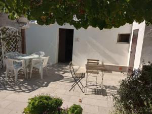 a patio with white chairs and a table and chairs at Trullo Il Giglio in Cisternino