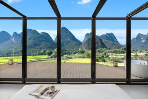 a room with a large window with a view of mountains at Paddy Fields Resort-Guilin Shuidaotian in Yangshuo