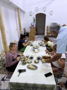 a group of people sitting around a table with food at Sarzamin Guest House in Khiva