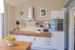 eine Küche mit weißen Schränken und einer Schale Obst auf dem Tisch in der Unterkunft Appartement in Klein Meckelsen mit Eigener Terrasse - b43026 in Klein Meckelsen