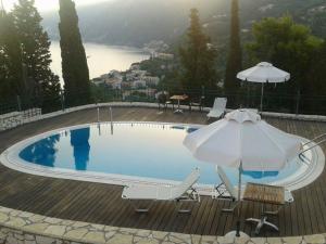basen z parasolem, krzesłami i stołem w obiekcie Villa Milia w mieście Agios Nikitas