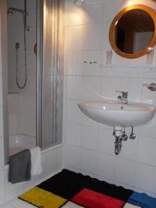 La salle de bains blanche est pourvue d'un lavabo et d'une douche. dans l'établissement Ferienwohnung Nationalparkblick, à Spiegelau