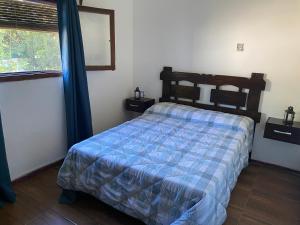 a bedroom with a bed with a blue comforter and a window at No reservar por aquí es publicación duplicada in Piriápolis