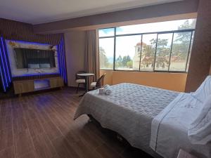 una camera d'albergo con un letto e una grande finestra di Kapricho Wanka a Huancayo
