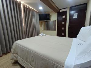 una camera da letto con un grande letto bianco e una televisione di Kapricho Wanka a Huancayo