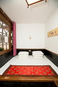 a bedroom with a bed with red sheets and a window at Pingyao Xiangshengyuan Guest House in Pingyao