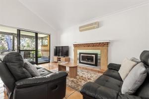 ein Wohnzimmer mit zwei Sofas und einem Kamin in der Unterkunft Acorn Delight - Tranquil Retreat by the Golf Course in Dunsborough